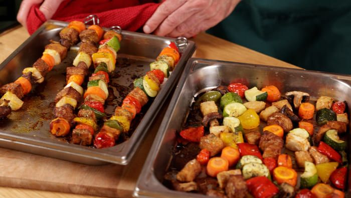Brochettes et légumes rôtis disposés dans deux plats