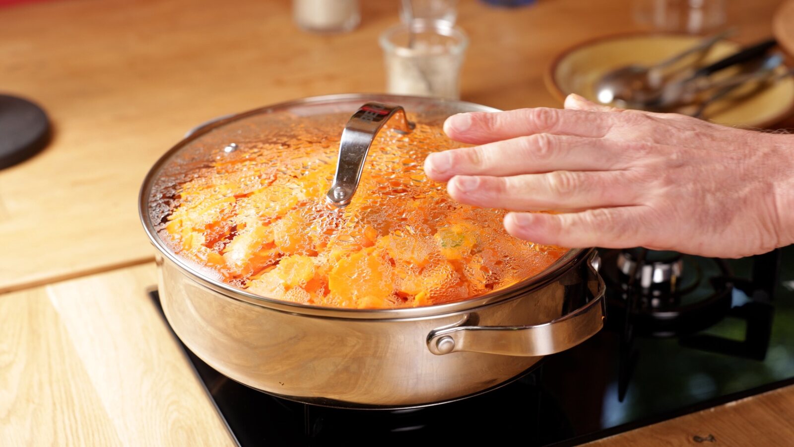 Main soulevant le couvercle d’une sauteuse de légumes