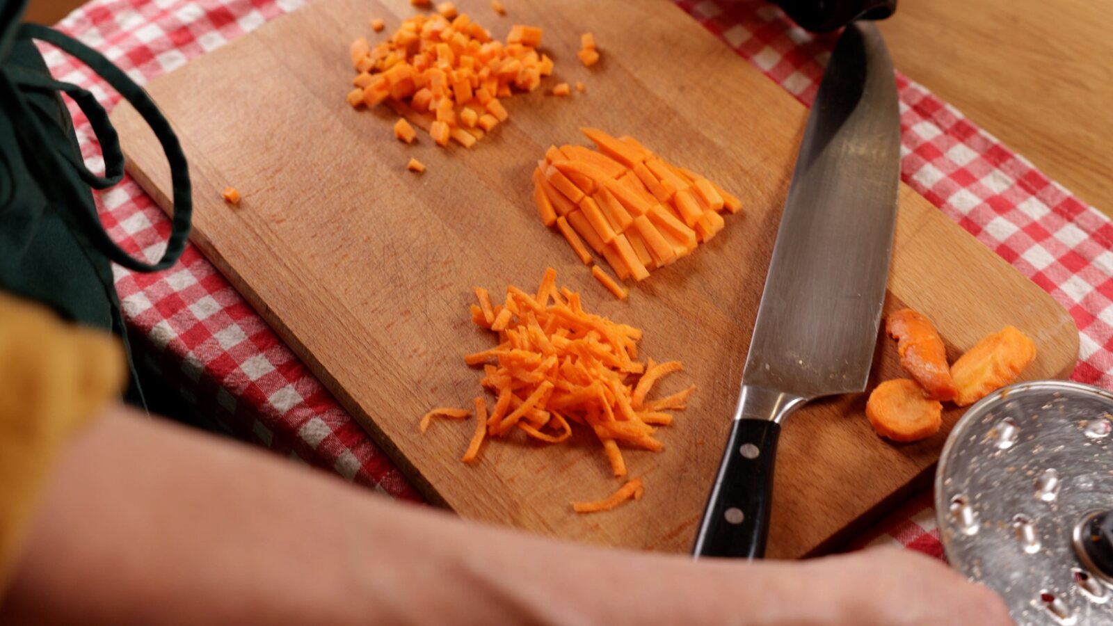 Mains découpant des carottes sur une planche en bois