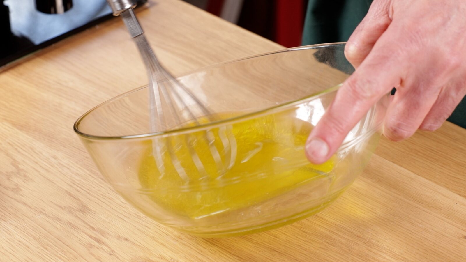 Main fouettant une sauce jaune dans un récipient