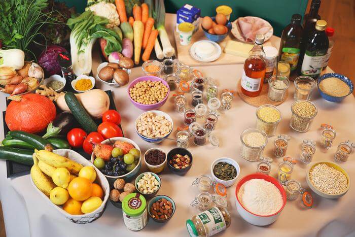 Une table remplie d'ingrédients naturels : légumes, fruits, noix, céréales et huiles